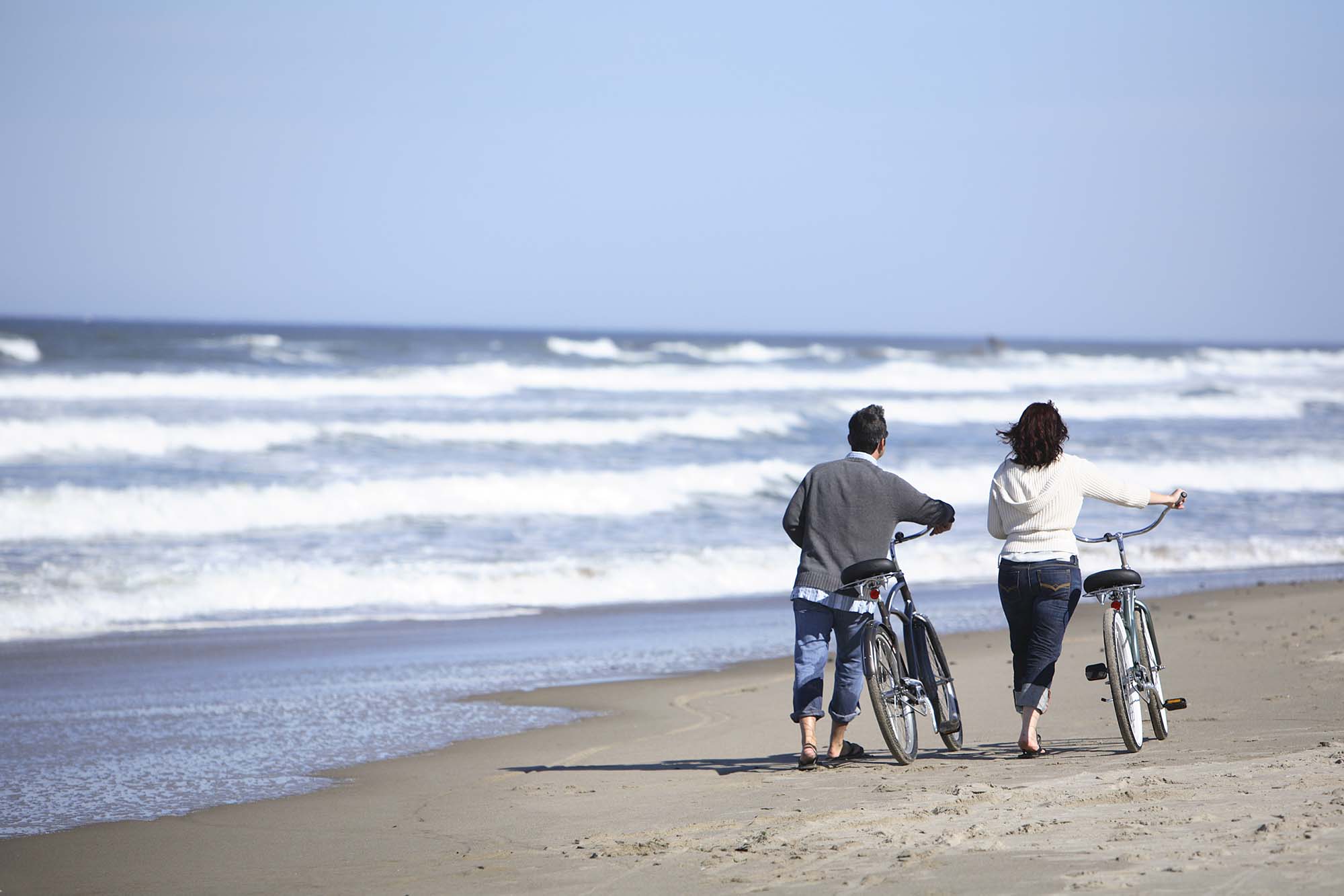 Couple walking on beach with bikes